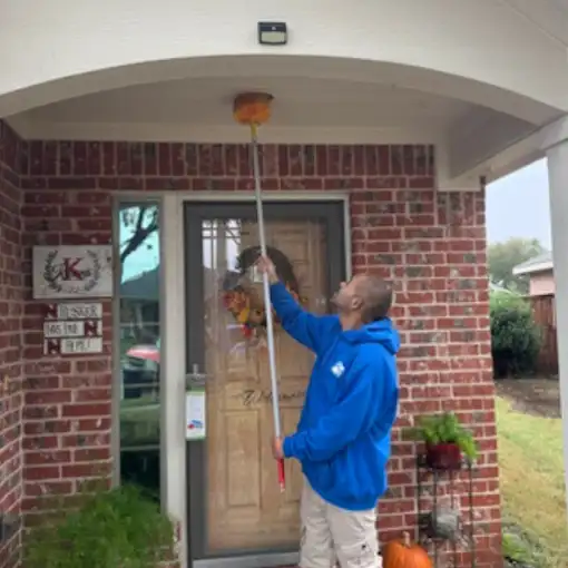 Buffalo Outdoor technician sweeping a porch ceiling and eave with a web pole