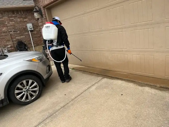 Technician treating the base of a garage door, a common entry point for pests and rodents