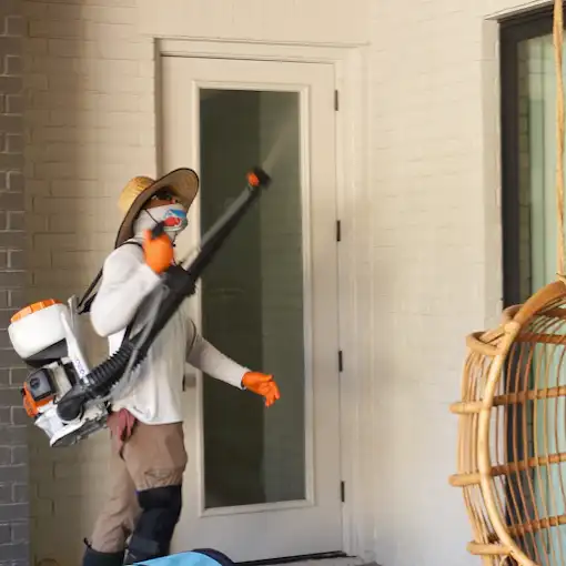 Buffalo Outdoor technician in protective gear treating a door frame with a backpack mist blower