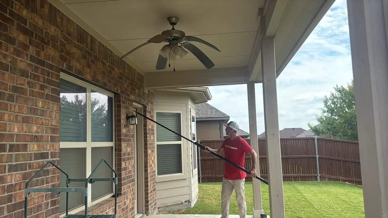 Buffalo Outdoor technician removing spider webs from porch eaves and ceiling with a web pole