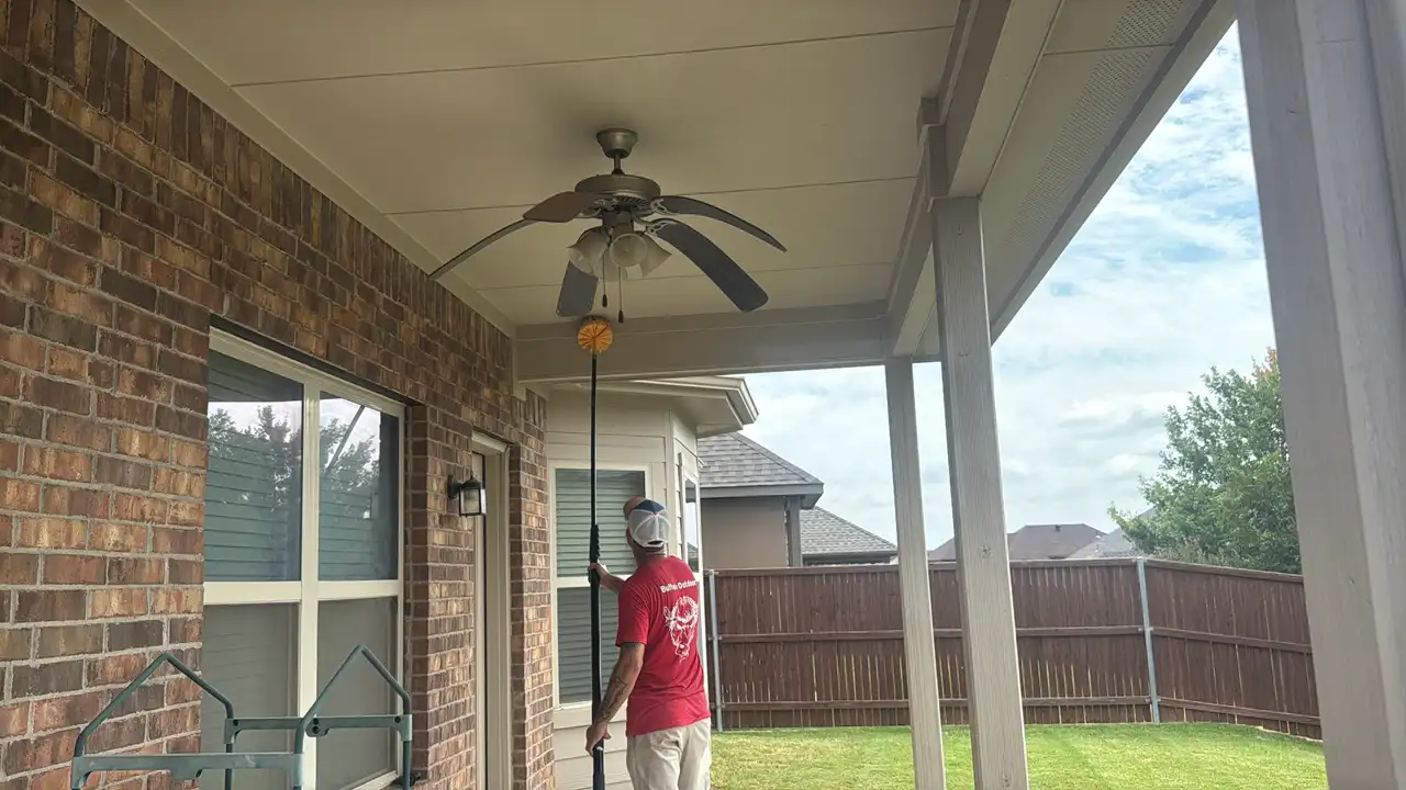 Buffalo Outdoor technician sweeping a porch ceiling and eaves with a web pole