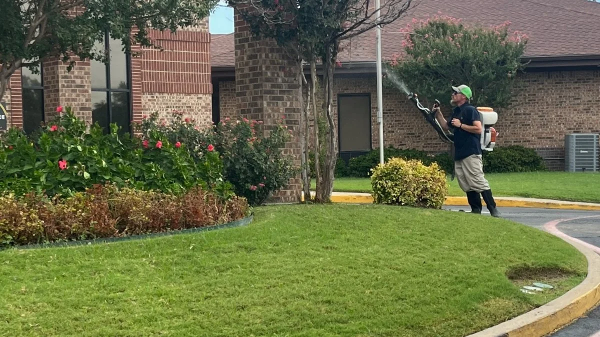 Buffalo Outdoor technician treating a yard in front of a North Texas brick home